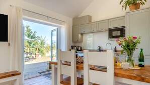 A modern kitchen with a dining area, a sliding glass door to a patio, and a view of the outdoors.