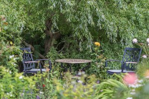 A garden setting with a table and chairs under a tree. - 3 Bed in Hastings (oc-h32649) (Three Oaks)