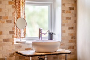 A bathroom with a white sink, a round mirror on a stand, and a window with curtains. - 3 Bed in Hastings (oc-h32649) (Three Oaks)