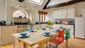 Een moderne keuken met witte kasten, een houten eettafel voor zes personen en een dakraam erboven.