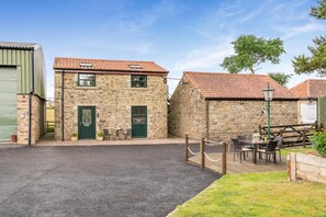 A stone building with a tiled roof, a green door, and a small outdoor seating area with tables and chairs. - 2 Bed in Crook (oc-s32614) (Crook)