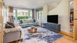 Ein geräumiges Wohnzimmer mit Sofa, Couchtisch und Flachbildfernseher.