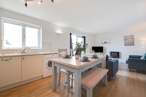 Eine moderne Küche mit Essbereich, einer Waschmaschine und einem Flachbildfernseher.
