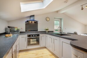 Eine moderne Küche mit Dachfenster, integriertem Backofen, Mikrowelle und Granit Arbeitsplatten.