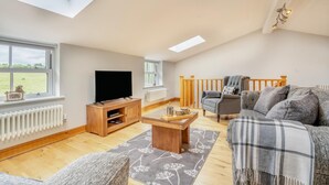 Een ruime woonkamer met een televisie, een houten tv-meubel en een gezellige bank.