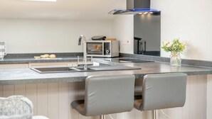 Een moderne keuken met een ingebouwde magnetron, een roestvrijstalen spoelbak en een zwarte afzuigkap.
