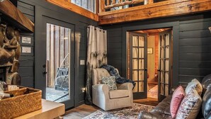 A cozy interior with a wooden ceiling, a beige armchair with a patterned pillow, a leather sofa with decorative pillows, and a patterned rug. - Hot Tub, Views, & True Smoky Mountain Charm! (Sevierville)