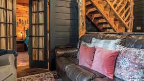 A cozy living room with a leather couch, a wooden staircase, and a rustic interior design. - Hot Tub, Views, & True Smoky Mountain Charm! (Sevierville)