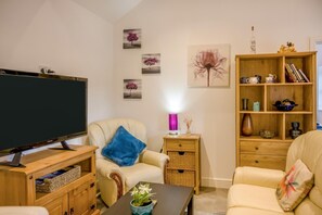 A living room with a television, a sofa, a coffee table, a bookshelf, and wall art. - 1 Bed in Gilsland (oc-h32687) (Waterhead)