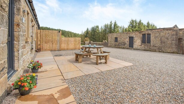 A courtyard with a picnic table, stone walls, and a wooden fence. - 1 Bed in Gilsland (oc-h32687) (Waterhead)