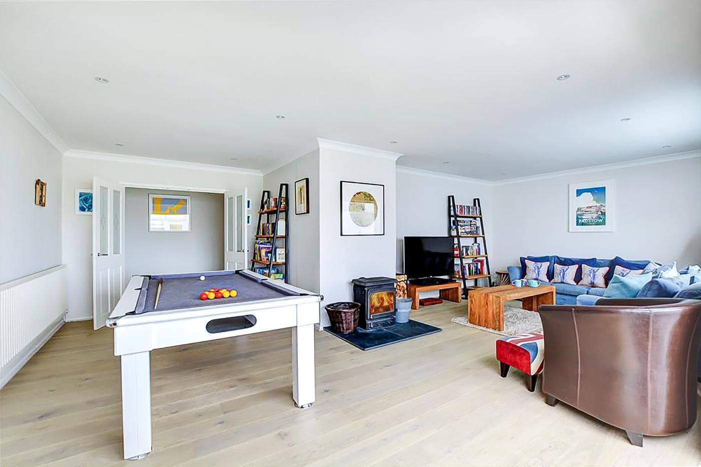 A living room with a pool table, a sofa, a television, and a fireplace.