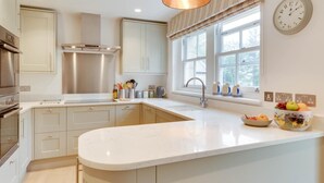 A modern kitchen with a large island, stainless steel appliances, and a window with a view. - 4 Bed in Ellingham (oc-gd1929) (Ellingham)