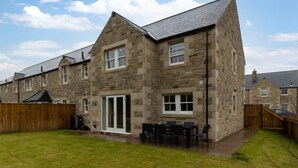 A stone house with a patio and outdoor seating. - 4 Bed in Ellingham (oc-gd1929) (Ellingham)