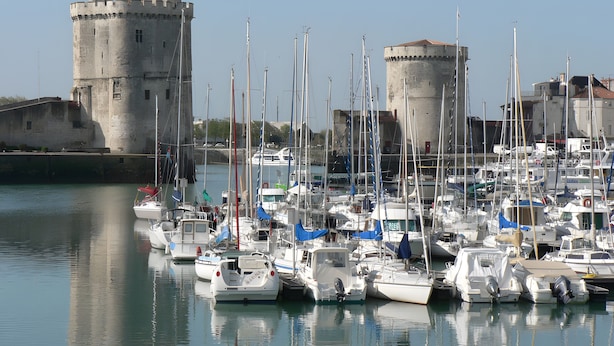 A marina with multiple boats docked, a castle-like structure in the background, and calm water. - Gîte de l'érable, 5 min from La Rochelle (Périgny)