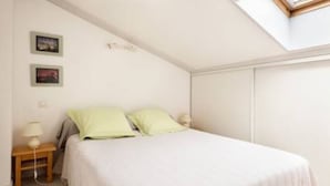 A bedroom with a bed, a nightstand, a lamp, and a skylight. - Gîte de l'érable, 5 min from La Rochelle (Périgny)