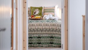 Ein Schlafzimmer mit einem geblümten Bettbezug, einem Kissen mit Eulenmuster und einem Korb voller Frühstücksleckereien.