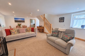 A living room with a sofa, a dining table, and a staircase. - 3 Bed in Ventnor (oc-o32663) (Chale)