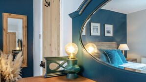 A bedroom with a wooden headboard, a mirror, a bedside table with a lamp, and a bed with blue bedding. - 3 Bed in Whitby (oc-w1018) (Whitby)