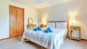 A bedroom with a bed, two bedside tables, a wooden door, and a hanging light fixture. - 3 Bed in Isle Of Skye (oc-s32340) (Glenhinnisdal)