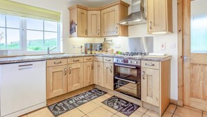 A modern kitchen with wooden cabinets, a stainless steel range hood, and a built-in oven. - 3 Bed in Isle Of Skye (oc-s32340) (Glenhinnisdal)