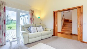 A living room with a sofa, a small table, and a staircase leading to another level. - 3 Bed in Isle Of Skye (oc-s32340) (Glenhinnisdal)