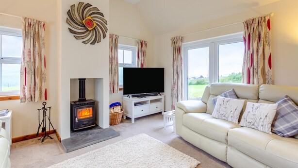 A cozy living room with a fireplace, a television, and a sofa with decorative pillows. - 3 Bed in Isle Of Skye (oc-s32340) (Glenhinnisdal)