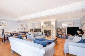 A spacious living room with a dining area, a fireplace, a bookshelf, and a television. - 6 Bed in Bacton (oc-2187) (Bacton)