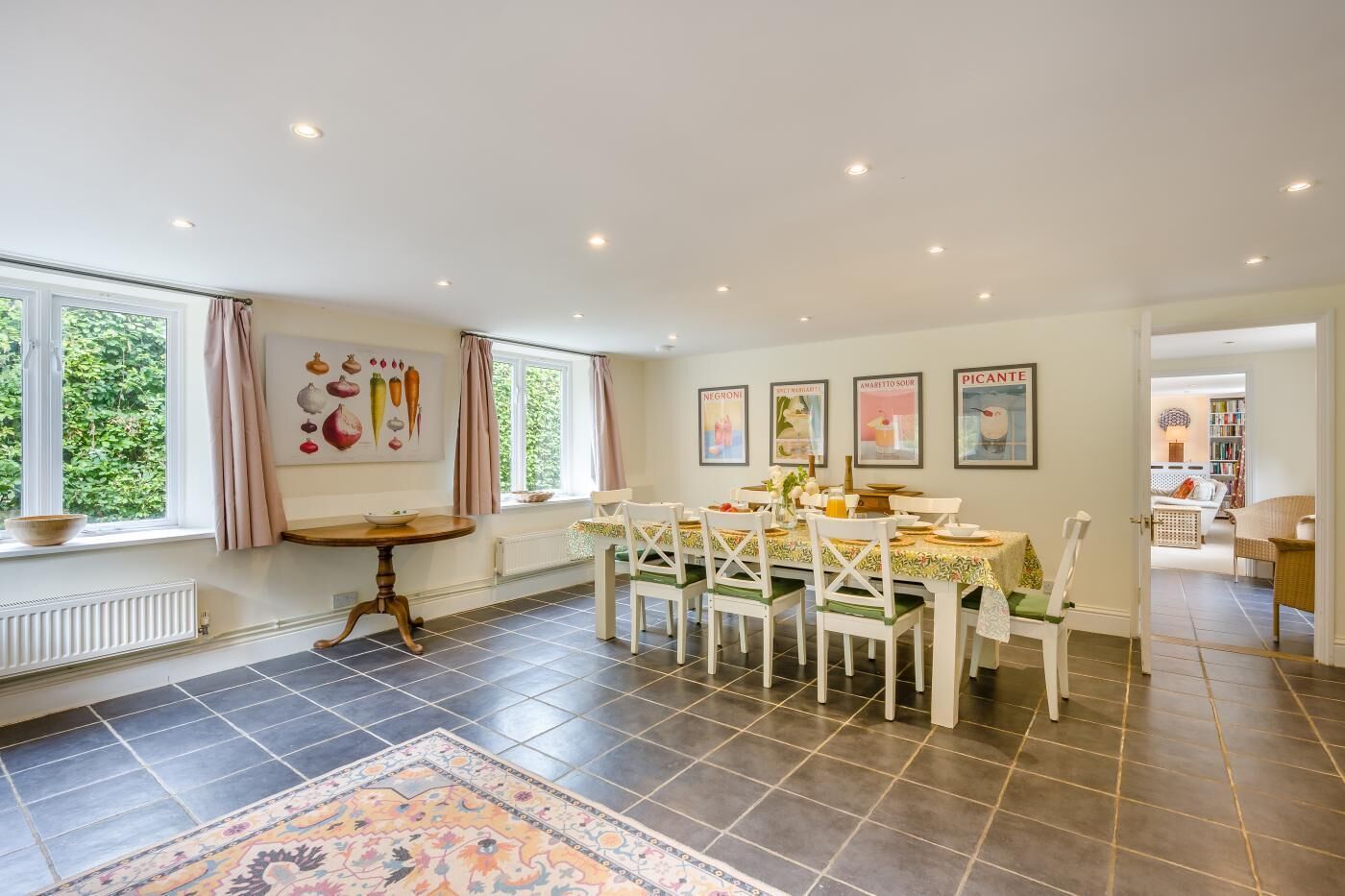 A dining area with a round table, white chairs, and a patterned rug.