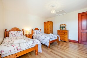 A bedroom with two wooden beds, a wooden wardrobe, and a dresser. - 3 Bed in St Columb (oc-trembl) (Saint Mawgan)