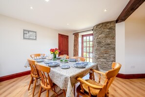 Ein Essbereich mit einem Marmortisch, Holzstühlen, einer Blumenvase und einer Steinwand.