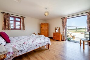 Ein Schlafzimmer mit einem Bett, einem Holzkleiderschrank, einem Wandschrank und einem Balkon mit Sitzgelegenheit.