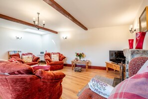 Ein Wohnzimmer mit roten Sofas, einem Holztisch, einem Fernseher und einem Kamin.