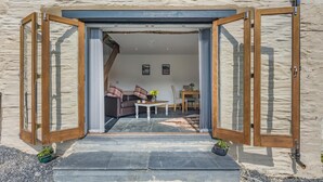 An open doorway leading to a living area with a sofa, a coffee table, and a dining table. - 1 Bed in Abergynolwyn (oc-p32345) (Abergynolwyn)
