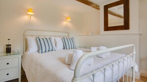 A neatly made bed with white bedding and striped pillows, a bedside table with a coffee pot, and a wall-mounted mirror. - 3 Bed in Holt (oc-2150) (Holt)