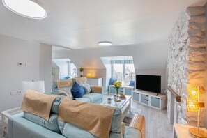 A modern living room with a sofa, coffee table, and TV. - 2 Bed in Dyffryn Ardudwy (oc-f32356) (Dyffryn Ardudwy)
