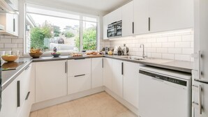 Una cocina moderna con armarios blancos, un refrigerador de acero inoxidable y una ventana que ofrece vistas al exterior.