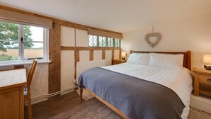 Ein Schlafzimmer mit einem hölzernen Bett, einem Schreibtisch und einem Fenster mit Blick ins Freie.