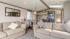 A modern living room with two sofas, a dining area, and a kitchen. - 2 Bed in Hendra Croft (oc-h32360) (Croft)