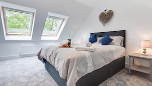 A modern bedroom with a large bed, skylights, and a heart-shaped wall decoration. - 3 Bed in Llanfynydd (oc-pw9215) (Llanfynydd)