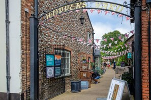 A quaint street with a sign reading "HOPKINS YARD" and various small shops and stalls. - 1 Bed in Holt (oc-2176) (Holt)