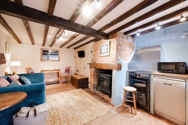 A cozy living room with a fireplace, a dining area, and a kitchen with modern appliances.