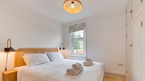 Ett sovrum med en stor säng, två sänglampor, ett fönster med utsikt och en garderob.