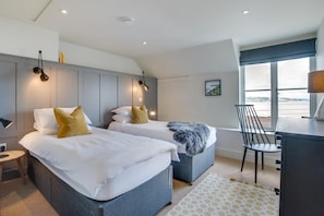 A hotel room with two beds, a desk, a chair, and a large window offering a view. - 4 Bed in Mumbles (oc-hh1222) (The Mumbles)