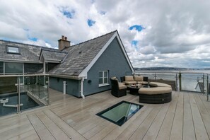 A deck with outdoor furniture, a glass balustrade, and a view of the sea. - 4 Bed in Mumbles (oc-hh1222) (The Mumbles)