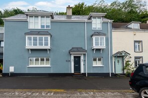 A two-story residential building with a dark blue exterior, white-framed windows, and a dark blue door. - 4 Bed in Mumbles (oc-hh1222) (The Mumbles)