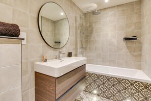 Une salle de bain moderne avec une baignoire sur pieds, un meuble-lavabo avec miroir et un espace douche.