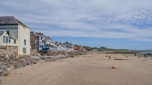 Une plage de sable bordée de bâtiments en pierre.