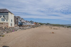 Ein sandiger Strand mit Steinhäusern entlang der Küste.