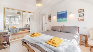 Ein Schlafzimmer mit einem großen Bett, einem Spiegel, einem Nachttisch und einem Sessel.