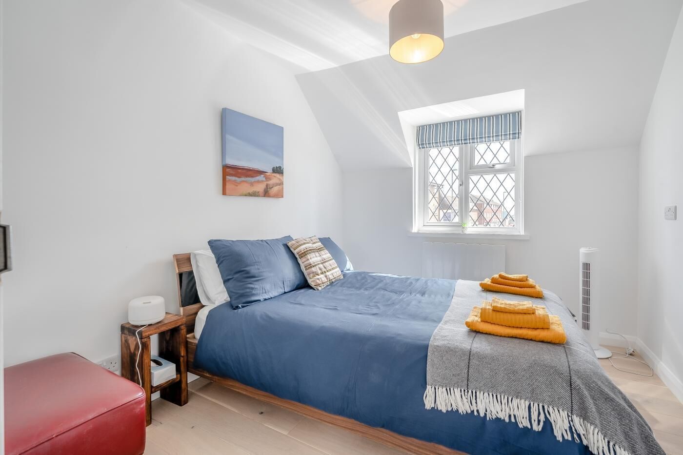 Ein Schlafzimmer mit Bett, Fenster mit Blick, Nachttisch und einer roten Bank.